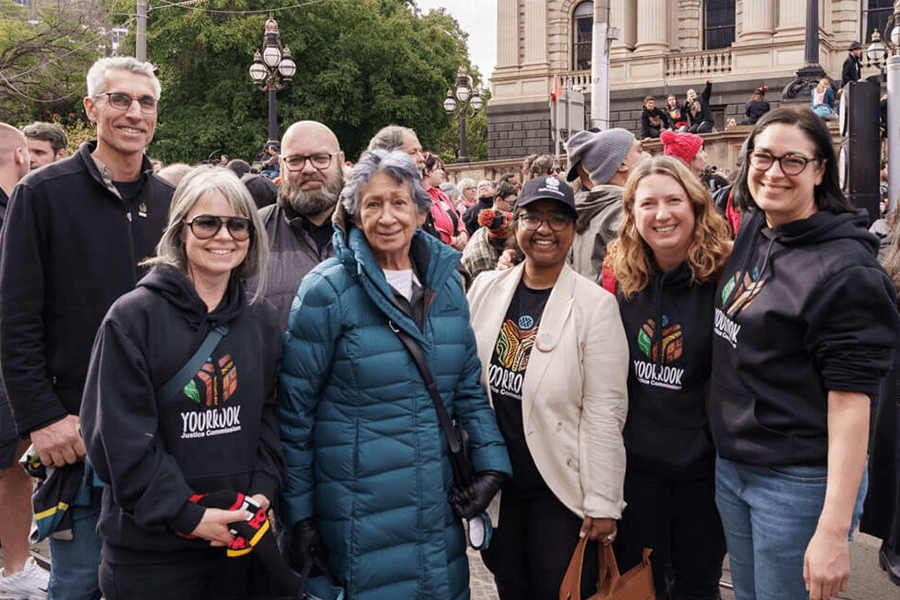 Yoorrook staff and Chairperson Eleanor Bourke standing together infront of parliament house at the NAIDOC march 2023