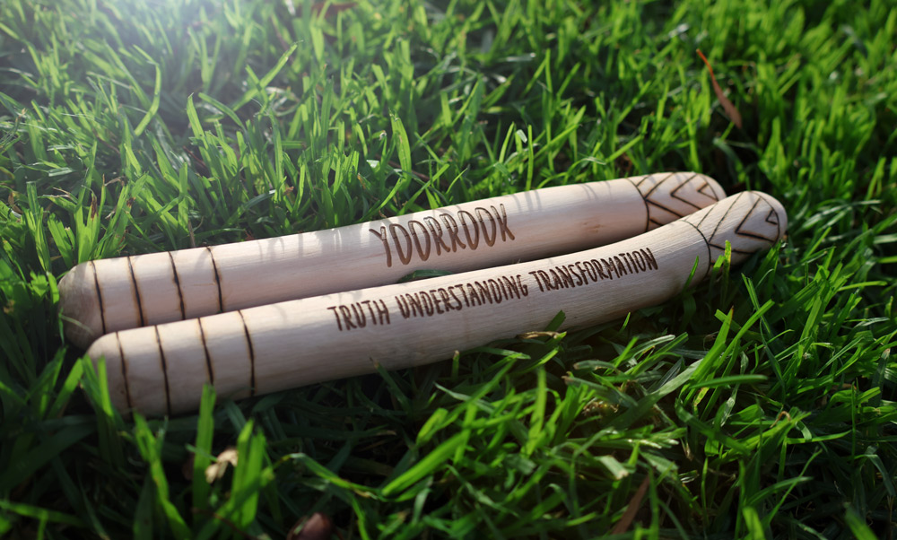 Yoorrook clap sticks on grass with Truth, Understanding, Transformation carved into them